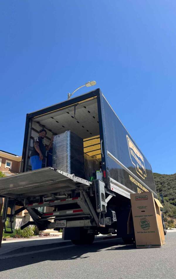 Hollywoodland Movers truck with lift gate down, mover inside.